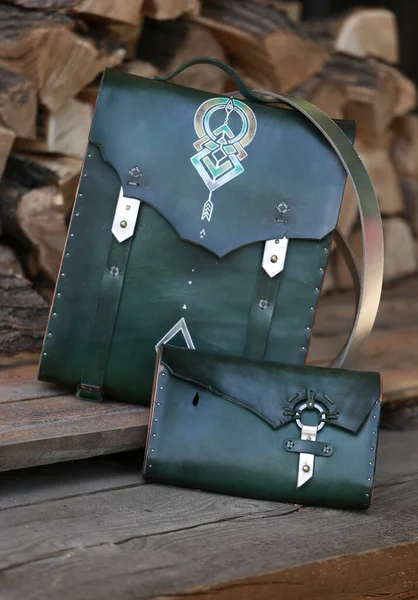 Yeşil deri cüzdanı olan sırt çantası, yakacak odununun arka planında.