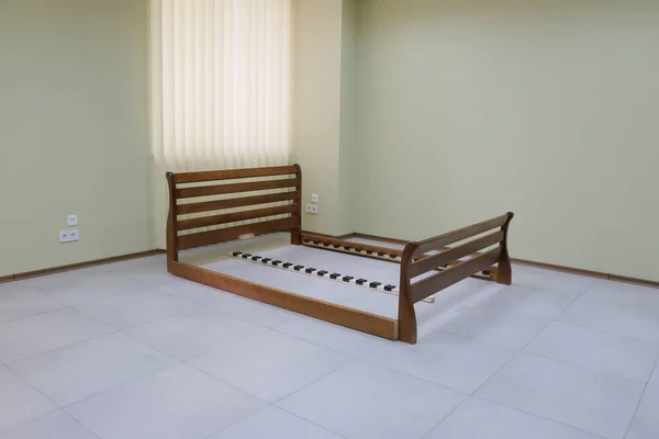 frame of a double wooden bed in the room without mattress