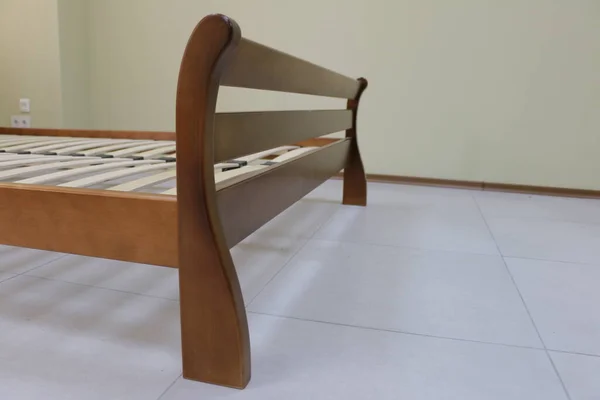 frame of a double wooden bed in the room without mattress