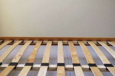 Döşeği olmayan tahtadan yapılmış sade bir yatak çerçevesi.