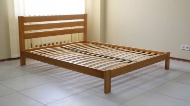 Döşeği olmayan tahtadan yapılmış sade bir yatak çerçevesi.