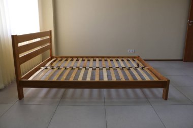 Döşeği olmayan tahtadan yapılmış sade bir yatak çerçevesi.