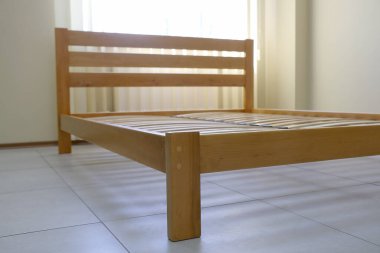 Döşeği olmayan tahtadan yapılmış sade bir yatak çerçevesi.