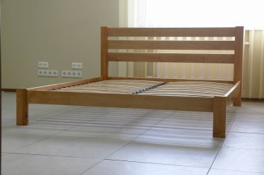 Döşeği olmayan tahtadan yapılmış sade bir yatak çerçevesi.