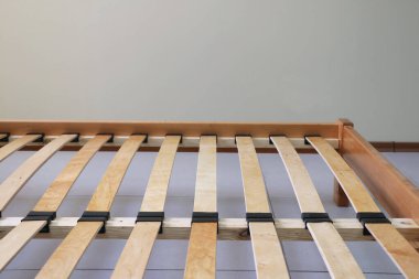 Döşeği olmayan tahtadan yapılmış sade bir yatak çerçevesi.