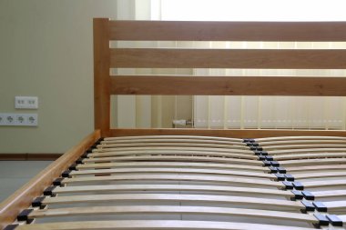 frame of a simple lacquered bed made of wood with slats without mattress clipart