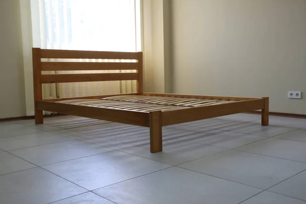 Döşeği olmayan tahtadan yapılmış sade bir yatak çerçevesi.