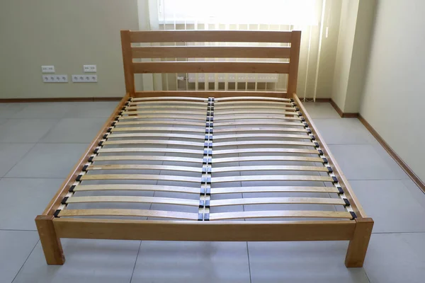 Döşeği olmayan tahtadan yapılmış sade bir yatak çerçevesi.