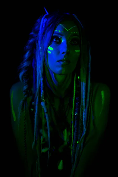 Portrait of Young naked bodyarted woman in blue glowing ultraviolet paint  with tomahawk ancient prehistorical weapon. Agressive avatar warrior   with pigtails hairstyle Stock Photo by ©tomasadzke 273678318