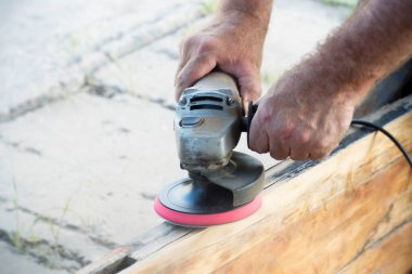 Manüel açılı öğütücüyle tahtayı cilalayan adam, yakın plan.