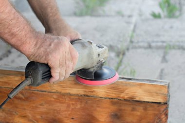 Tahtayı manuel öğütücüyle cilalayan adam, yakın plan.