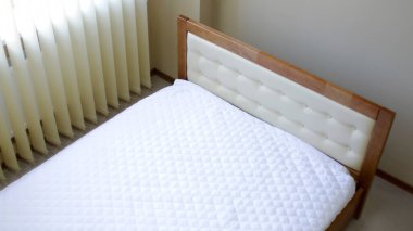 Ahşap kaplamalı çift kişilik yatak, döşemeli yatak başlığı.