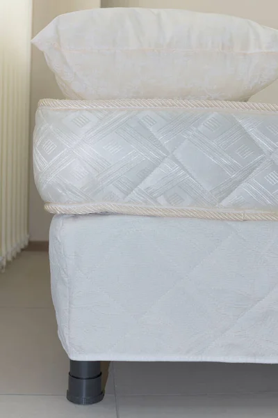 elements of a double bed frame with soft mattress cover and pillows, close-up