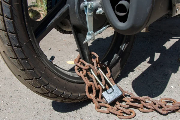 motorcycle wheel fastened with a rusty chain and lock, close-up
