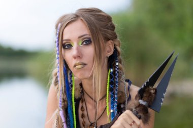 Girl with a spear look at the camera, close-up on the background of the lake