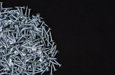 Dağınık metal vidalar, siyah kumaş üzerinde
