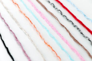 multi-colored threads of yarn laid out on a white background, close-up