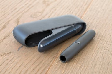 Ahşap bir yüzeyde geleneksel sigaraya alternatif olarak tütün ısıtma cihazı.