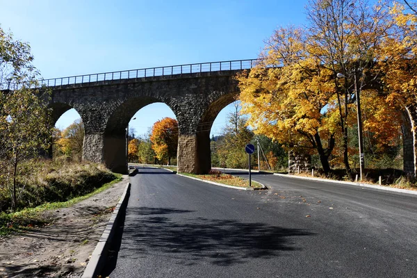 antique railway bridge over the road in autumn, Carpathians, Ukraine