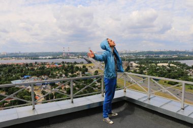 a guy on the roof of a multi-storey building with outstretched arms against the background of the urban landscape. Kyiv, Ukraine