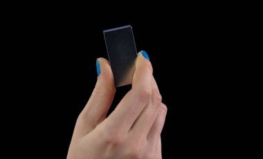 neodymium magnet in a female hand on a black background