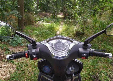 steering part with the dashboard of an electric motorcycle, on the driver's side, on a forest path