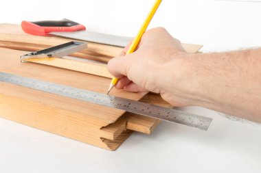 Beyefendinin eli, beyaz bir arka planda, kapı imalatı için ahşap bir boşluğu işaretler.