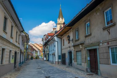 Slovenya 'nın ortaçağ kenti Kranj' ın Cankarjeva caddesinin panoramik manzarası, eski tarihi evleri ve güneşli bahar gününde Cantianus ve Refakatçi Kilisesi kulesi.