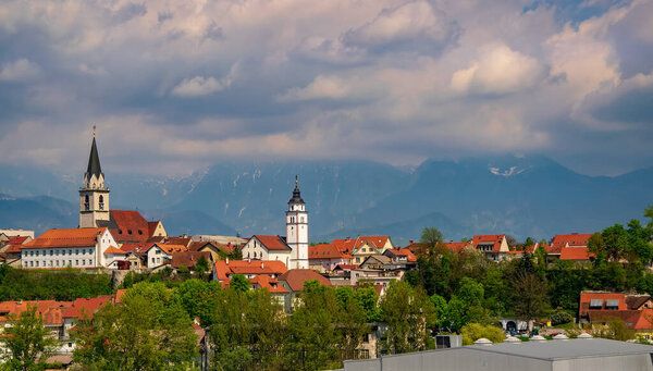 Panoramic view of old churches and historical city center of Kranj, Slovenia with mountains covered by clouds on background