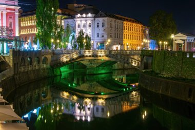 Aydınlatılmış Üçlü Köprü (Tromostovje) ve Mayer Sarayı 'nın gece manzarası Ljubljanica nehri, Ljubljana, Slovenya' da yansıdı. Latince 'de 