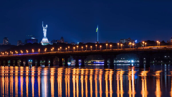 Scenic view of legendary metal Paton bridge across Dnieper river in Kyiv, Ukraine at the night. City lights reflected in the water