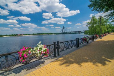 Embankment of Dnieper river in Natalka public park in Obolon district, Kyiv, Ukraine. North Cable Bridge on background