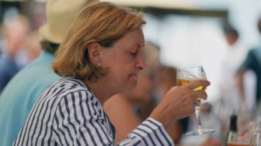 Restoranda oturmuş cam bira içen yaşlı bir kadın. Yaşlı bayan bir yudum serinletici içecek alır.