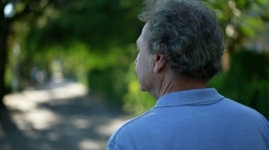 Kıdemli adam dışarıda, doğada yürüyor. Yürürken yaşlı birinin arkası