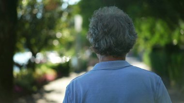 Kıdemli adam dışarıda, doğada yürüyor. Yürürken yaşlı birinin arkası