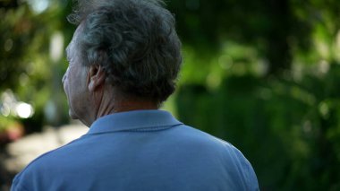 Kıdemli adam dışarıda, doğada yürüyor. Yürürken yaşlı birinin arkası