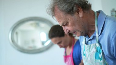 people cooking at home, candid granpa and adult daughter in kitchen preparing food