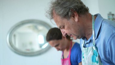 people cooking at home, candid granpa and adult daughter in kitchen preparing food