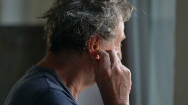 Yaşlı adam kulak tırmalayan kulak memesine dokunuyor.