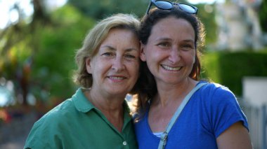 Anne ve yetişkin kızın birlikte kameraya baktığı portre.