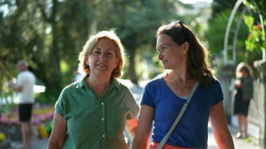 Yeşil şehirde birlikte yürüyen mutlu kadınlar, anne ve yetişkin kız