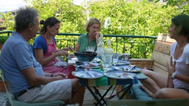 Aile öğle yemeği sırasında masada oturup yaz günlerinde sohbet ediyor.
