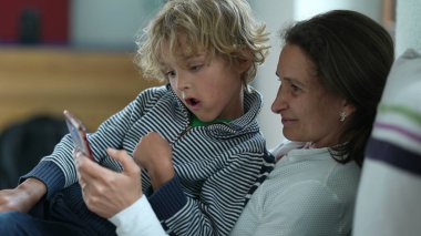 Dürüst anne ve çocuk koltukta otururken cep telefonundan memnun görünüyorlar.