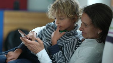 Dürüst anne ve çocuk koltukta otururken cep telefonundan memnun görünüyorlar.