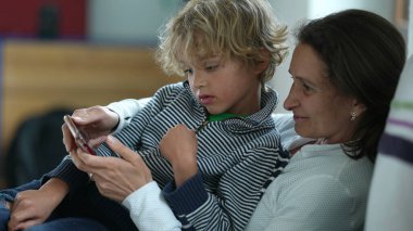 Dürüst anne ve çocuk koltukta otururken cep telefonundan memnun görünüyorlar.