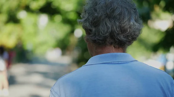 Smiling senior man walking outside in green path, one happy older person