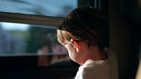 Small boy closing train window blind, child traveling by railroad