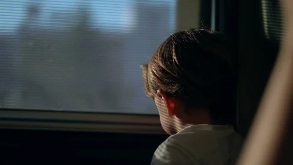 Small boy closing train window blind, child traveling by railroad