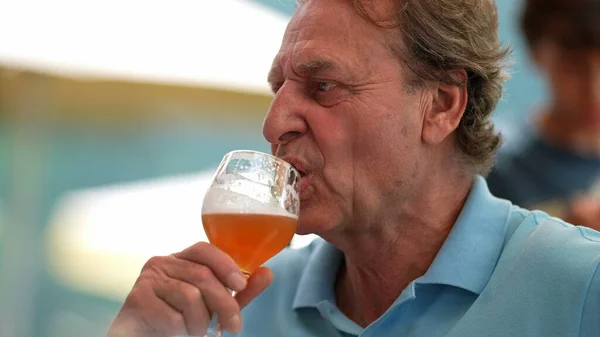 Senior person taking a sip of draft beer
