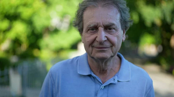 One happy older man walking outside during sunny day, pensive contemplative senior